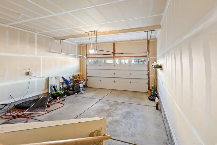 Spacious garage featuring a concrete floor, overhead lighting, and an automatic overhead door with transom window inserts