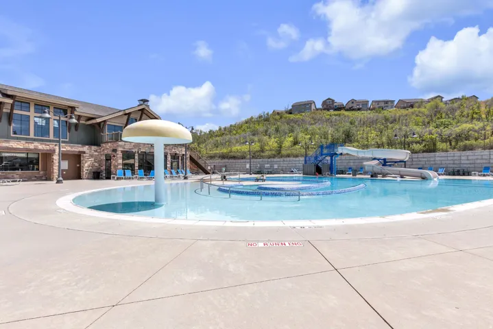 Community pool area featuring a large swimming pool, a circular wading pool with a mushroom-shaped water feature, and an additional pool with a water slide structure