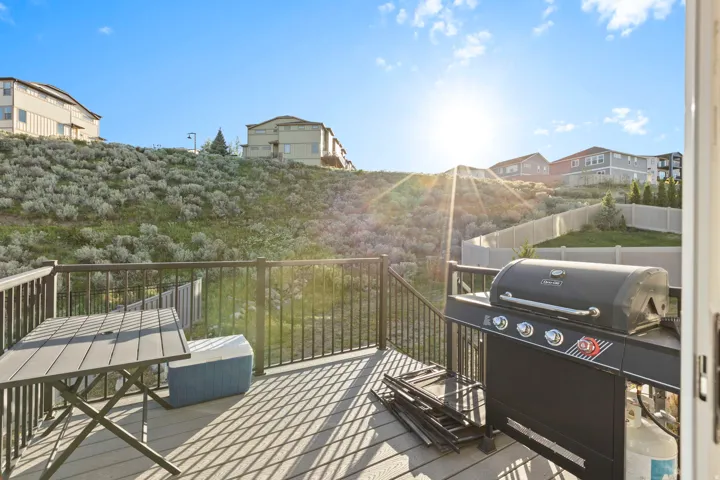 Outdoor deck featuring composite flooring, dark railings, and a sloped, natural landscape backdrop