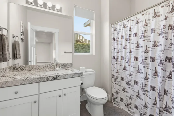 Bathroom vanity featuring a light-toned granite countertop with an integrated rectangular sink