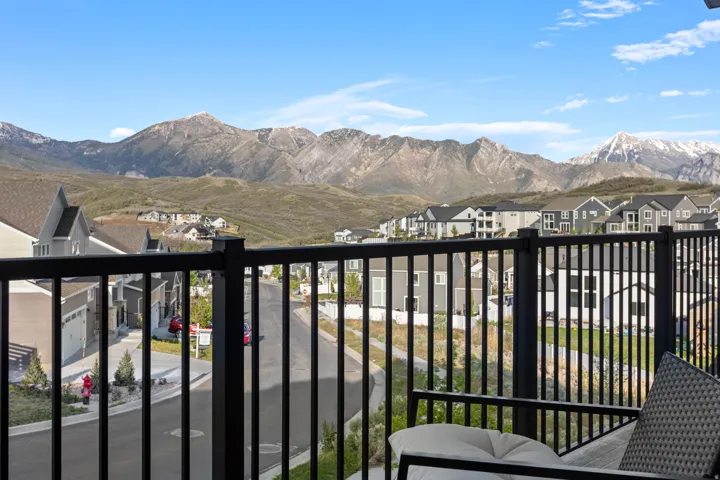 Balcony with a black metal railing overlooking a residential street and distant mountains