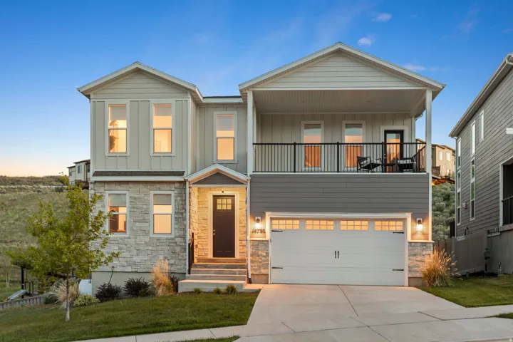 Contemporary exterior featuring a stone and siding facade, a covered entry, an upper-level balcony, a two-car garage with transom windows, and a concrete driveway