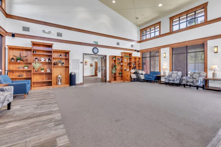 Spacious common area featuring vaulted ceilings, decorative wood-finish trim, built-in shelving, and large windows