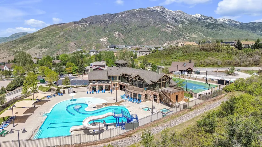 Community amenities featuring a large swimming pool with slide, multiple shaded seating areas, a hot tub, and a sports court