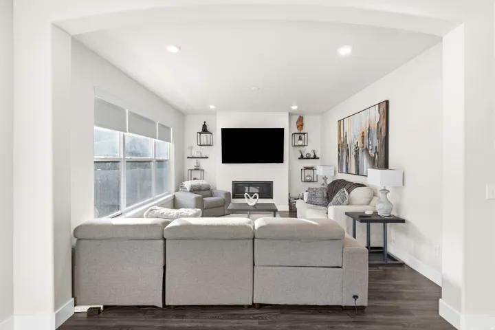 Open living area featuring dark wood-finish flooring, recessed lighting, and an arched entryway