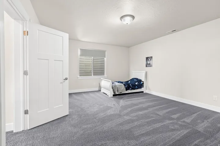 Carpeted room featuring a window with a roller shade, white trim, and a flush mount ceiling light