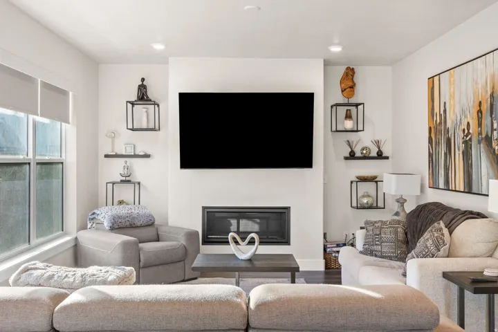 Living area featuring a mounted television above a built-in fireplace, recessed lighting, and large windows with roller shades