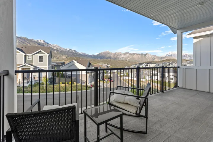 Expansive outdoor balcony featuring composite decking, black metal railings, and column supports, with distant mountain scenery