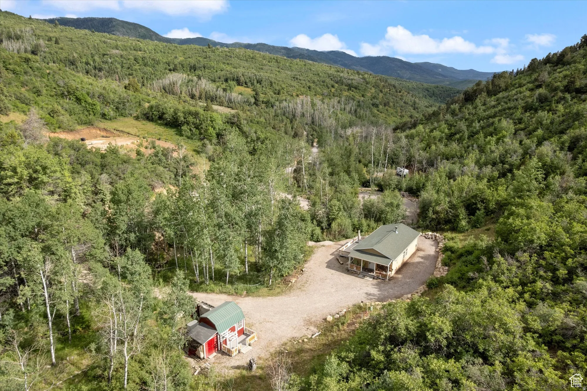 Aerial view of property and surrounding area featuring a forest and a mountain backdrop.