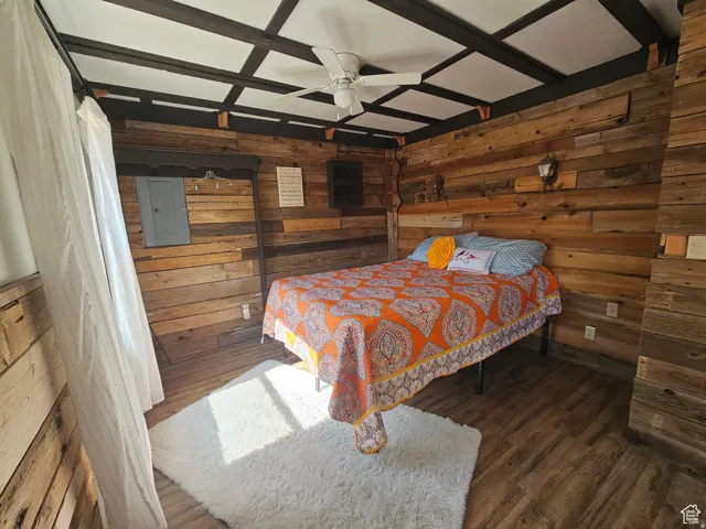 Bedroom featuring wood walls, a window, and ceiling fan.