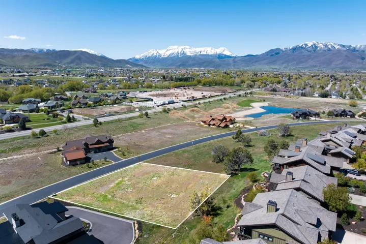 Cleared residential lot on a paved road, surrounded by established properties and distant mountain ranges