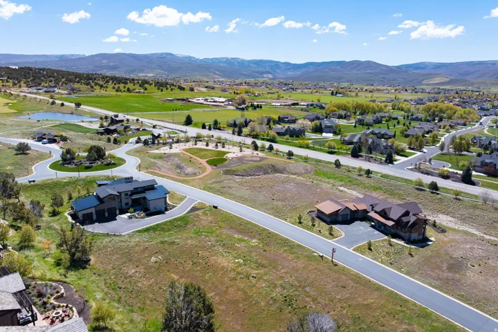 Aerial perspective capturing the residential development with a large pond and distant mountains