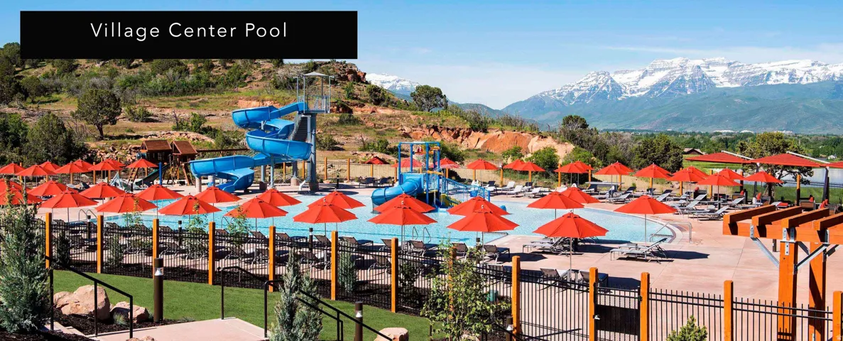 Expansive pool area featuring multiple water slides, numerous lounge chairs, and decorative red umbrellas