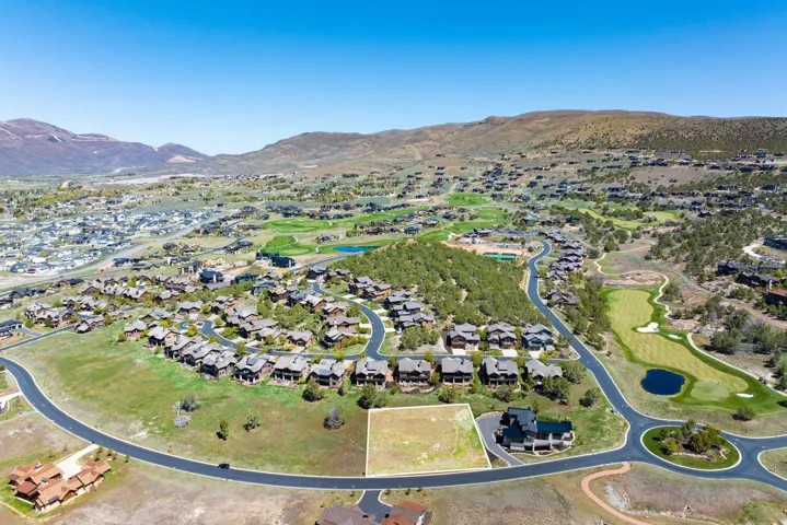 Expansive mountain landscape with a residential community, golf course, and paved roads