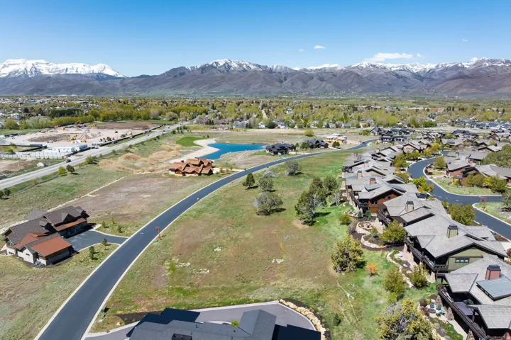 Expansive landscape featuring distant mountains, a natural pond, and surrounding residential development