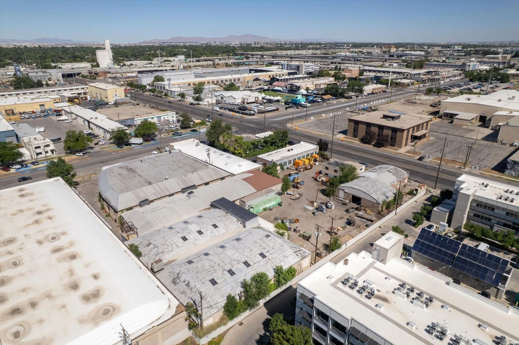 Aerial perspective of a commercial district featuring multiple industrial buildings with various roof styles including flat and curved structures