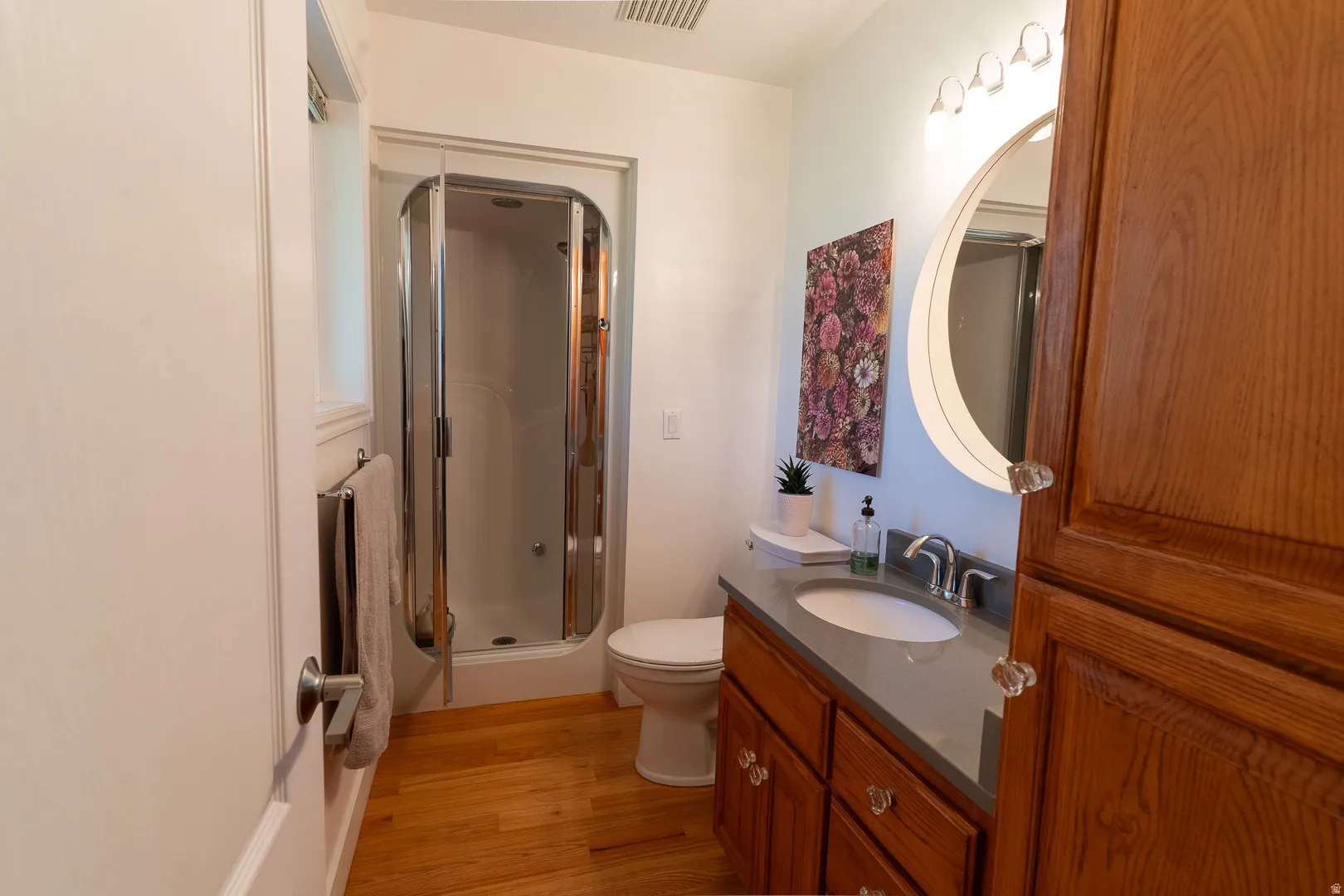 Three quarter bathroom, with wood floor, a glass-enclosed shower. Nice touches with mirror and design.