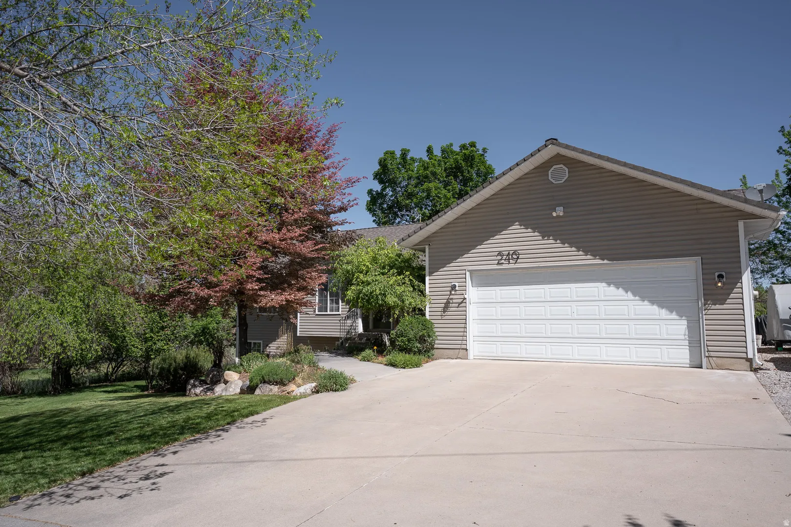 Extended two car garage, with side driveway, beautiful trees, and flowers line the pathway to the front door!