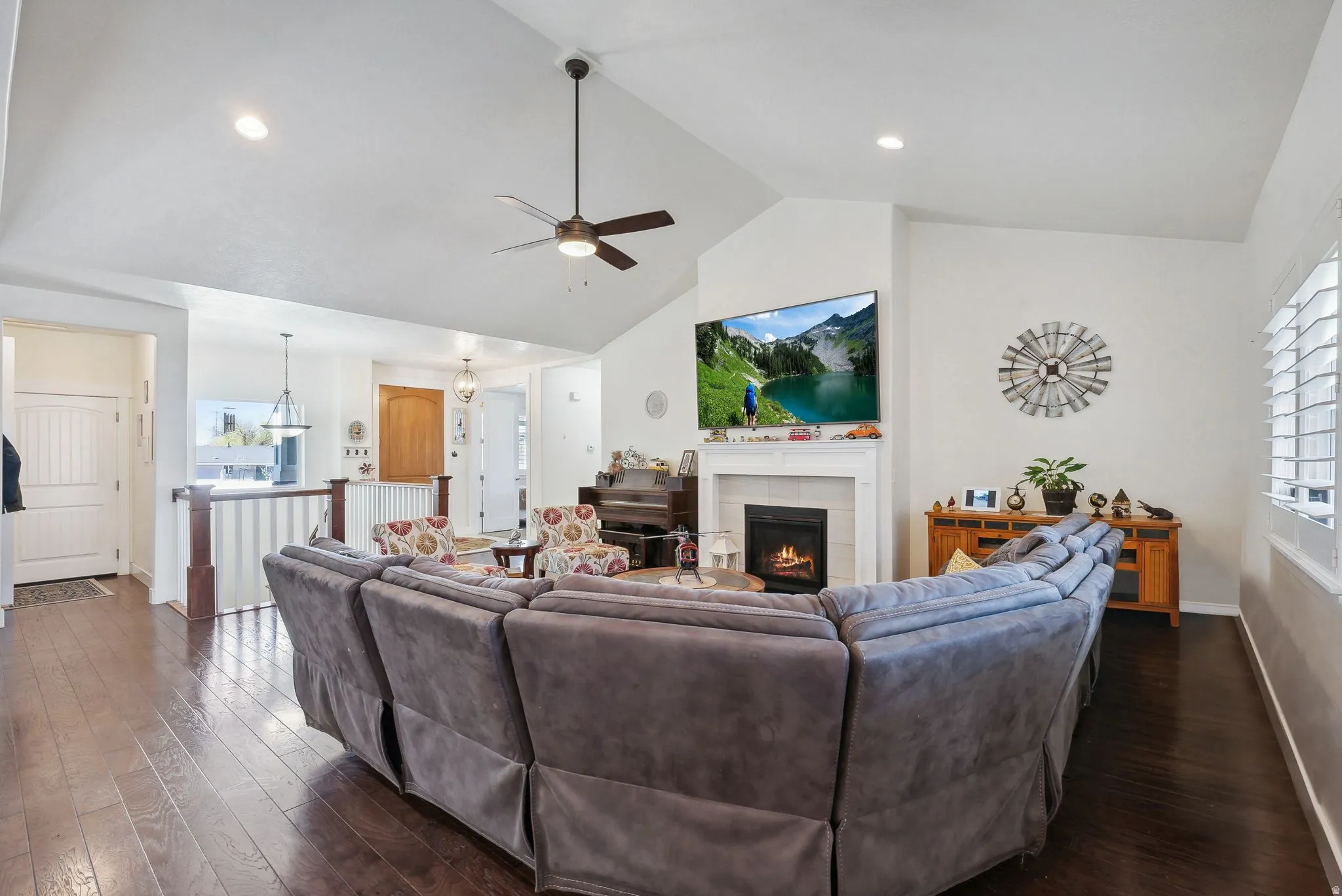 Vaulted ceilings enhance the living area, featuring wood-finish flooring and a corner fireplace with a white mantel