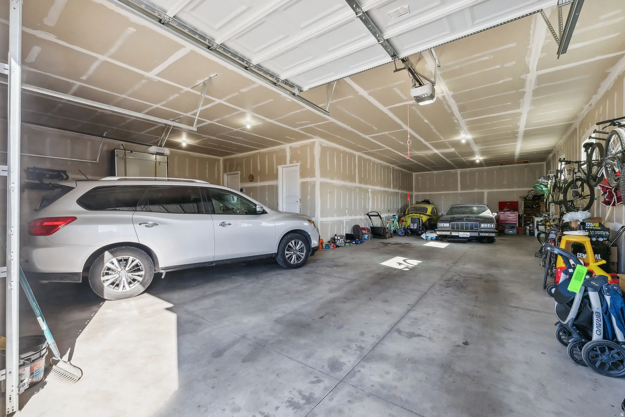 6 Car/ Spacious garage with multiple overhead lighting fixtures, exposed drywall, and concrete flooring