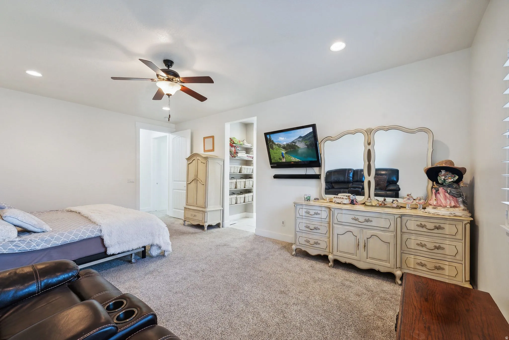 Spacious carpeted room featuring a ceiling fan with integrated lighting, recessed lighting, and a walk-in closet with built-in shelving