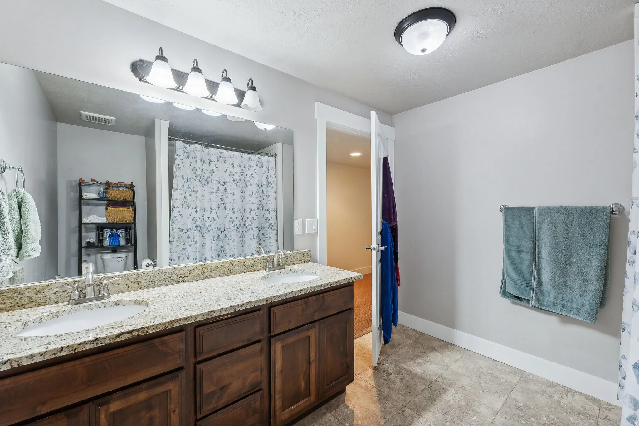 Bathroom featuring a dual vanity with light-colored speckled countertops, dark wood-finish cabinetry, and undermount sinks