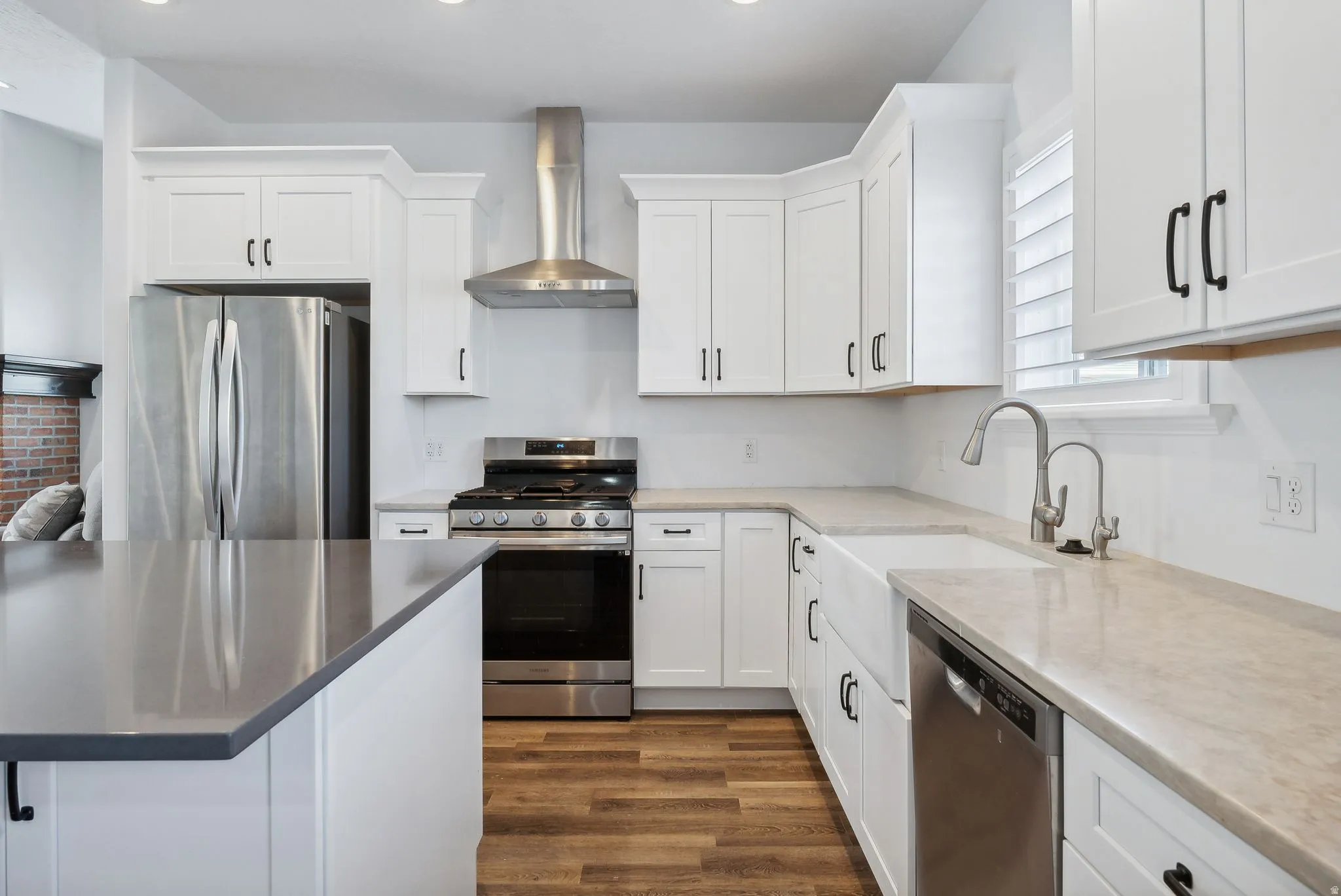 Custom built ADU/Modern kitchen featuring white shaker cabinetry, stainless steel appliances, wood-finish flooring, a farmhouse sink, and light-toned countertops