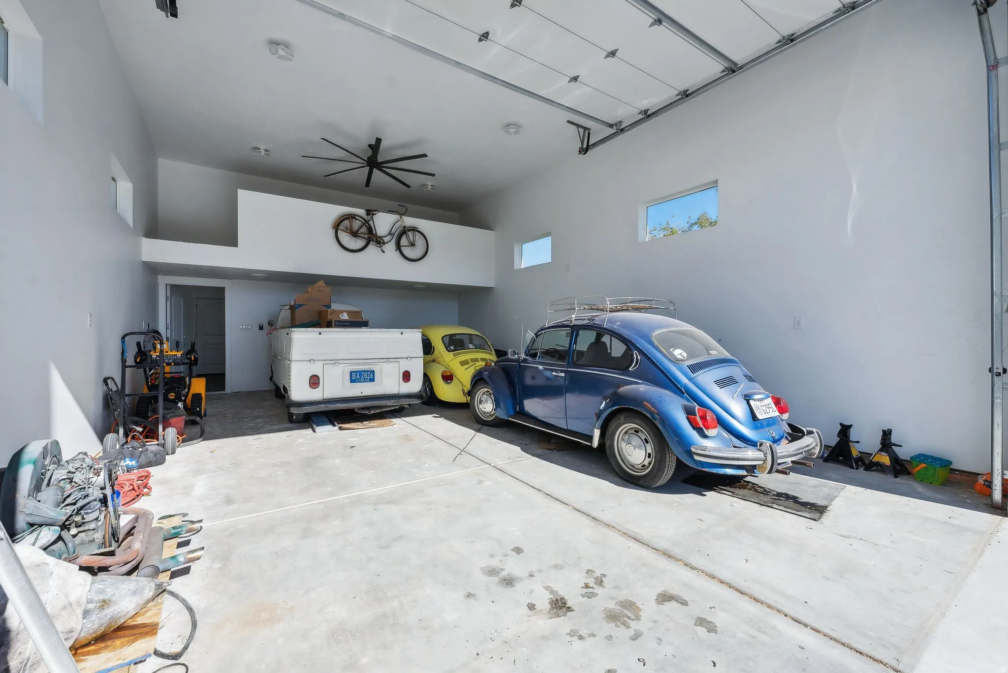 ADU / 4 car/Spacious garage featuring a large overhead door, concrete flooring, high ceilings, an integrated storage loft, and transom windows
