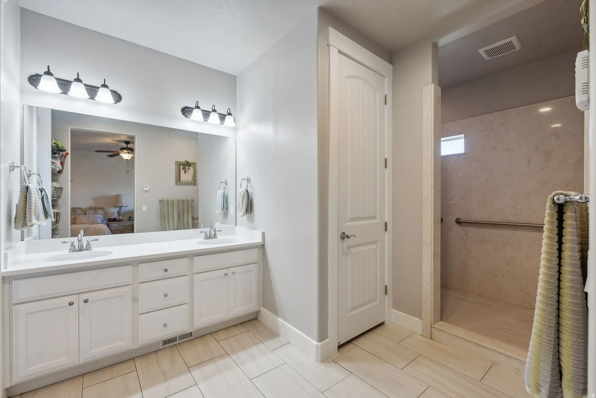 Bathroom featuring a double vanity with white cabinetry, dual sinks, and a large mirror