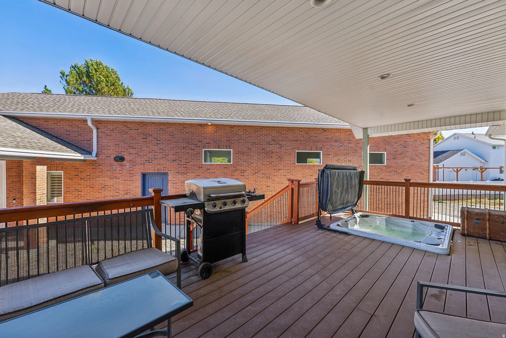 Spacious outdoor deck featuring composite decking, wood railing, and an integrated spa