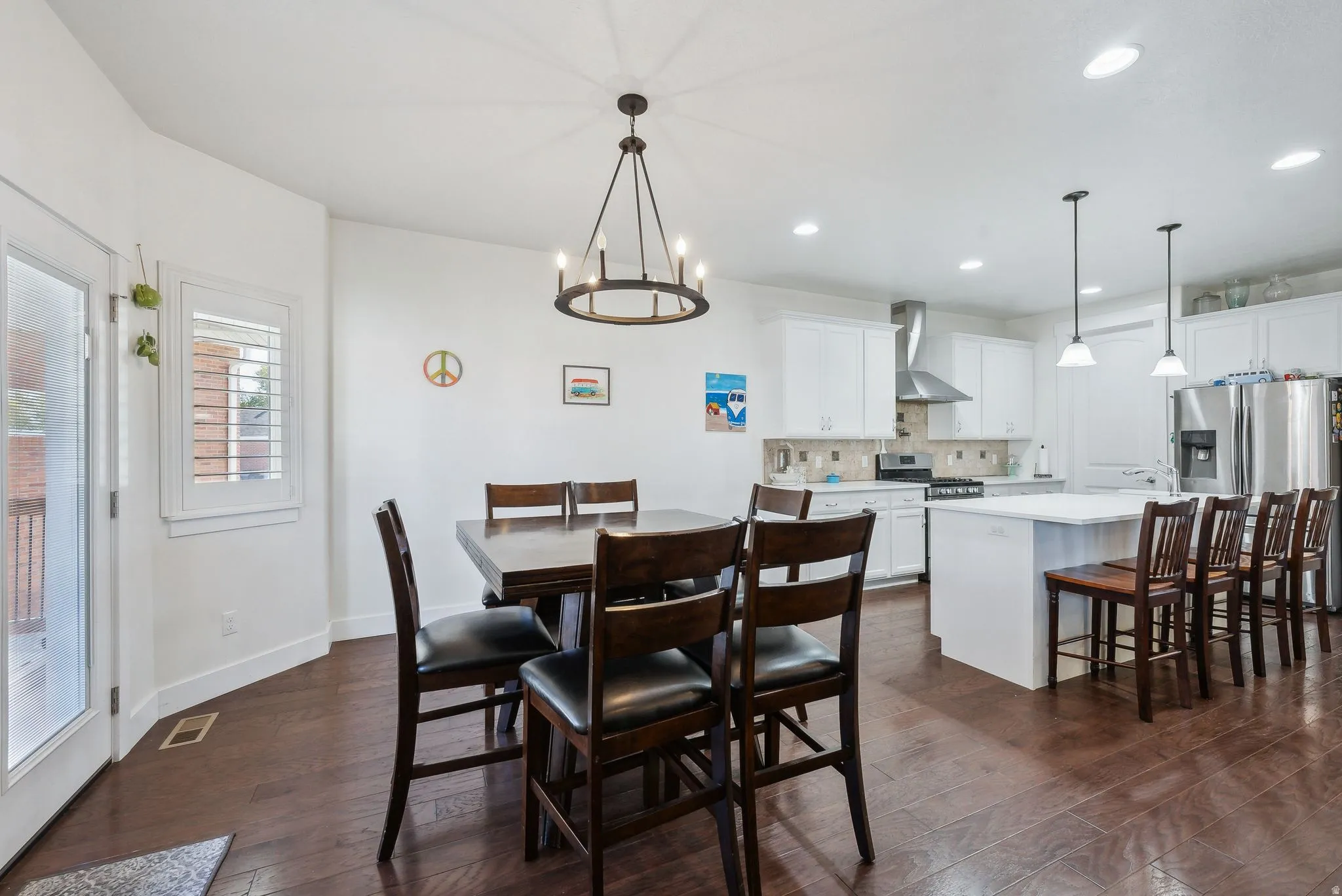 Open-concept kitchen and dining area featuring rich wood-finish flooring, white cabinetry, a large kitchen island with seating, stainless steel appliances, and recessed lighting