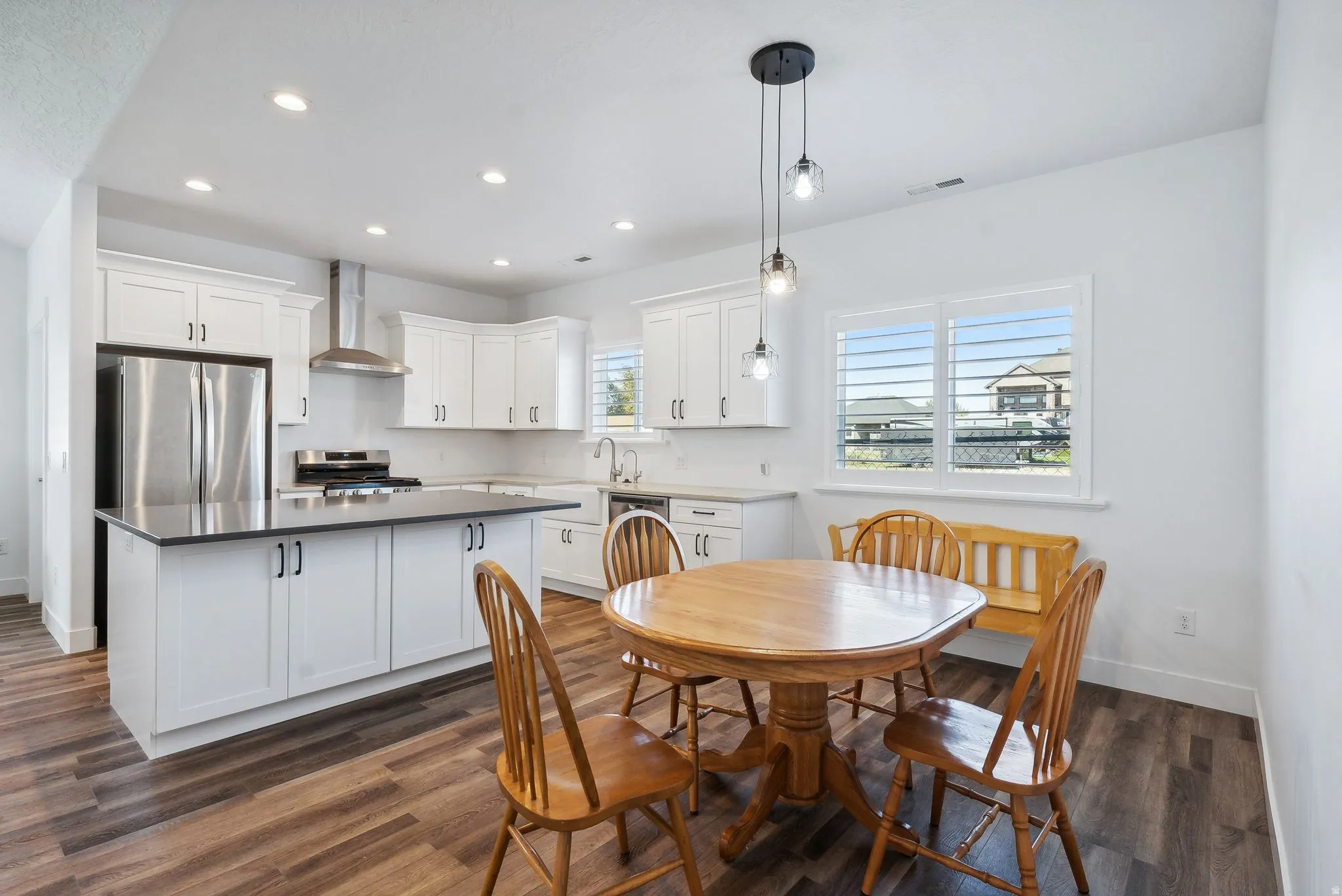 Custom built ADU/Contemporary kitchen featuring white cabinetry, stainless steel appliances, a center island with dark countertop, and wood-finish flooring
