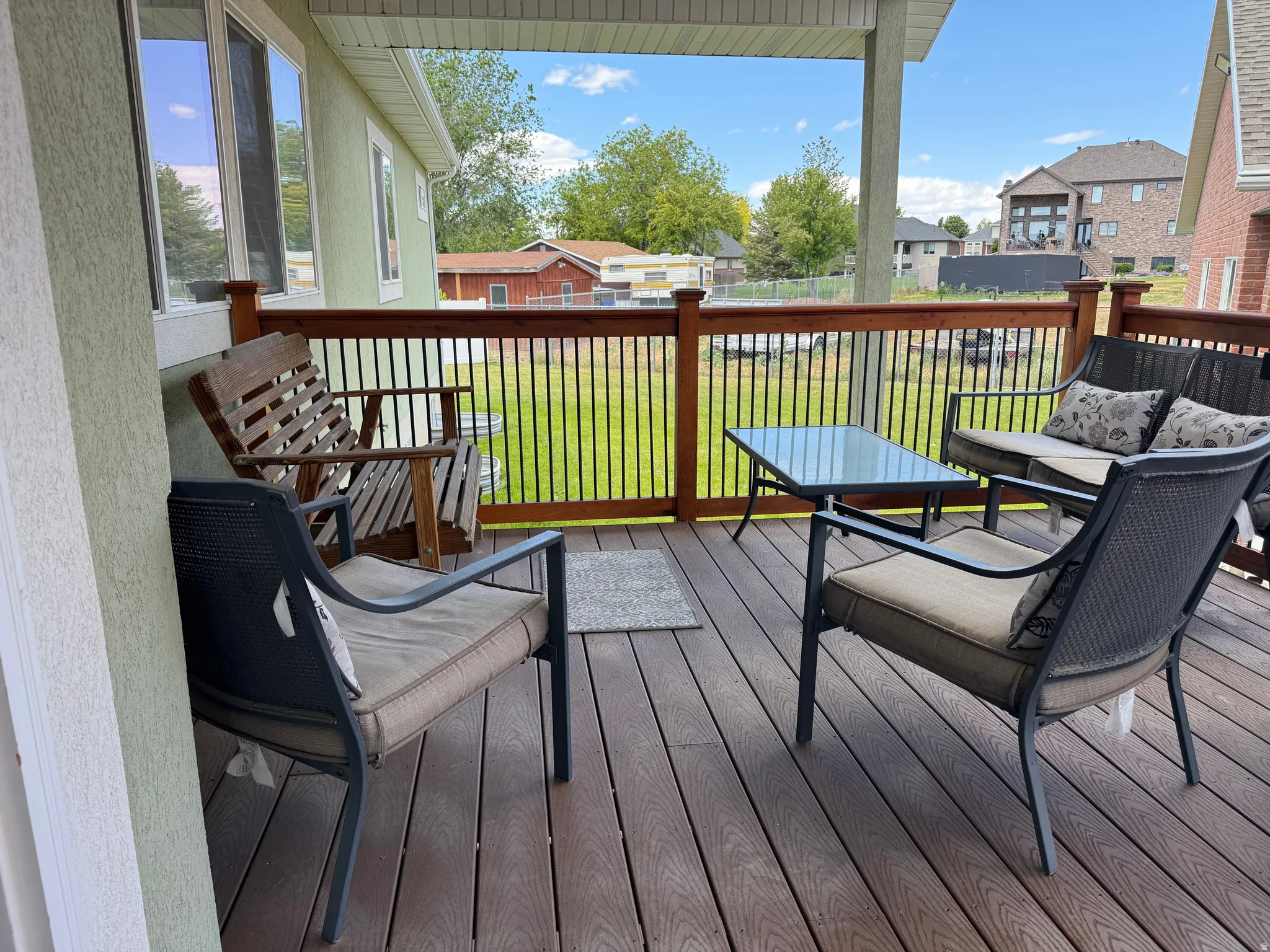 Expansive covered deck featuring composite decking and a wooden railing with black metal balusters