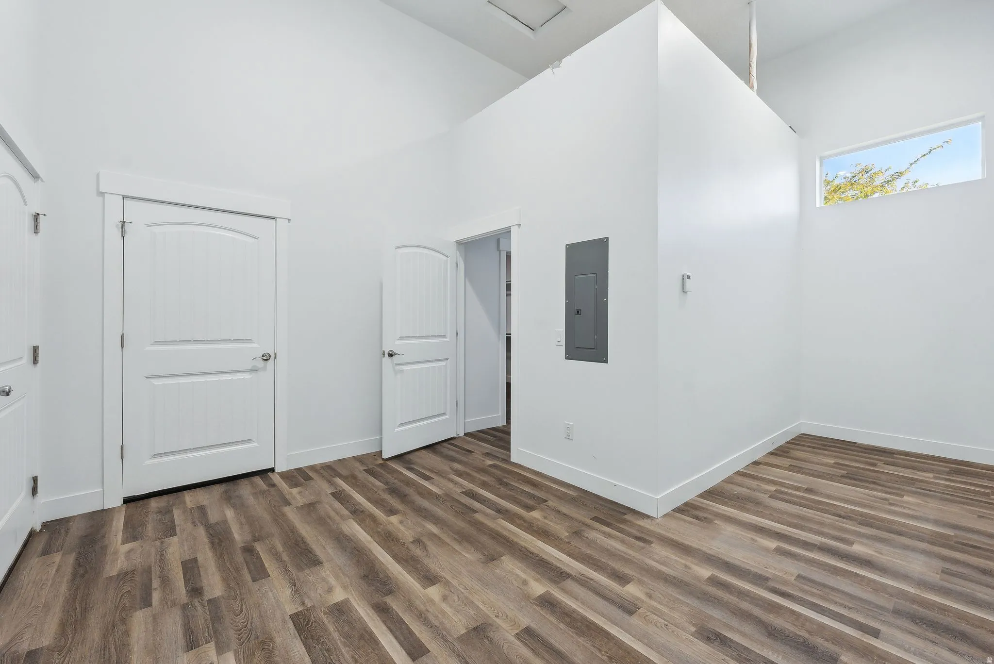 Custom built ADU/Spacious room featuring vaulted ceilings, wood-finish flooring, crisp white walls, and multiple paneled doors