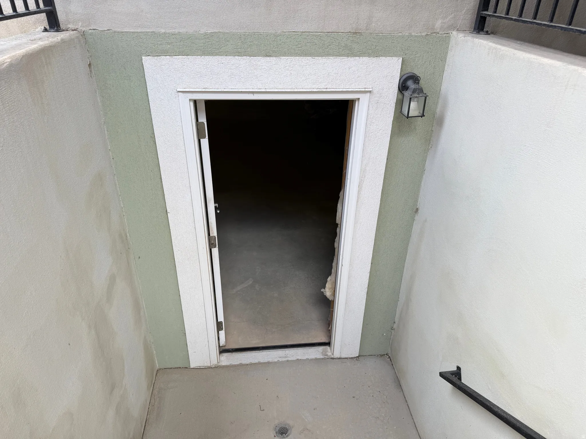 Recessed entryway featuring a painted stucco finish, white door casing, and a black exterior wall sconce