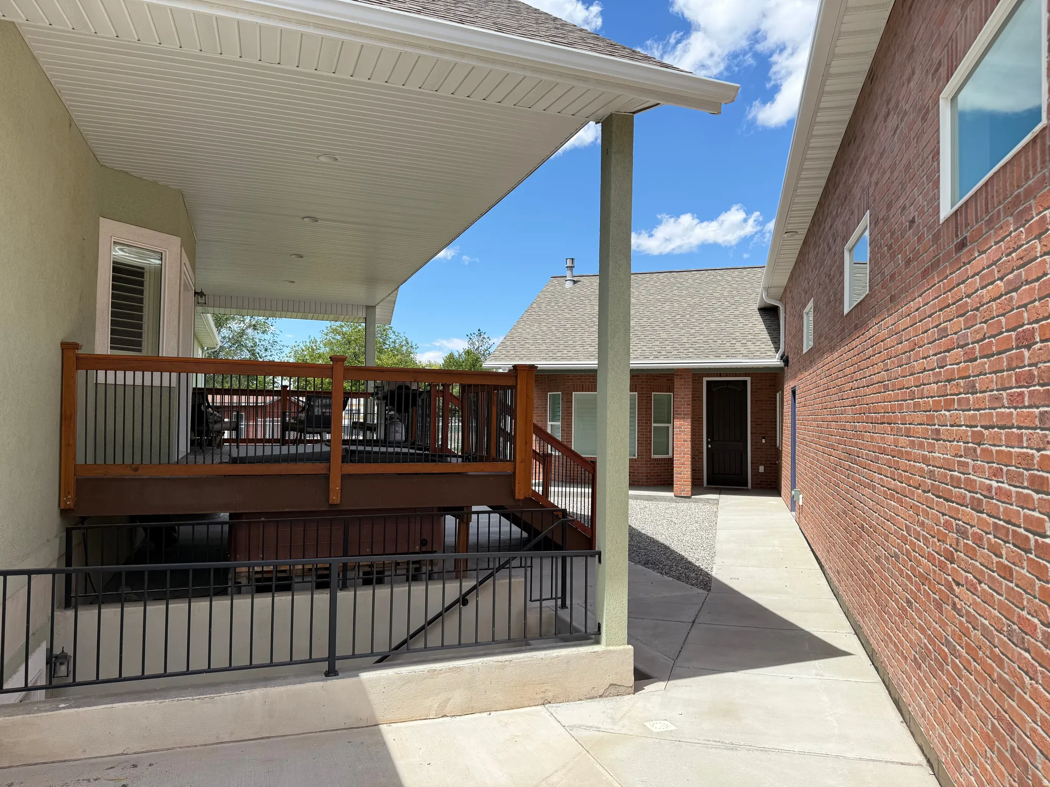 Covered patio with a wood-finish railing and black metal balusters