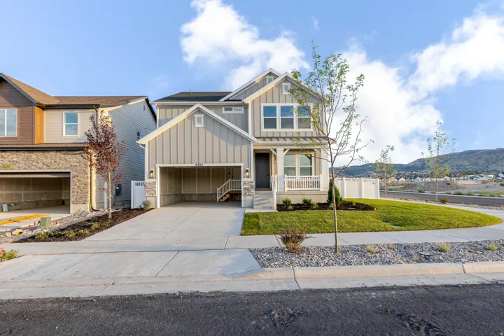 Contemporary residential exterior with board and batten siding, stone facade accents, and a covered porch