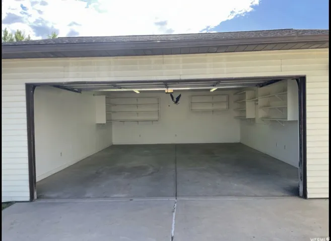 Two-car garage featuring a concrete floor, built-in shelving, overhead lighting, and horizontal siding exterior