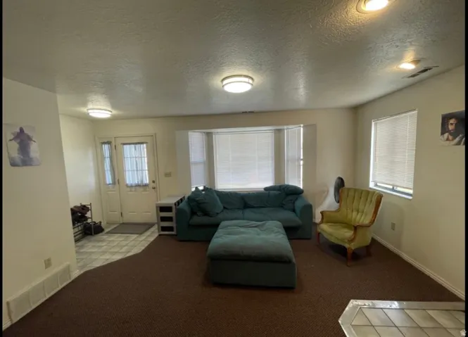 Living area featuring a bay window with blinds, recessed lighting, and a textured ceiling