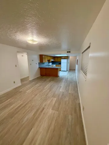 Open-concept living area featuring wood-finish flooring, textured ceilings, and recessed lighting