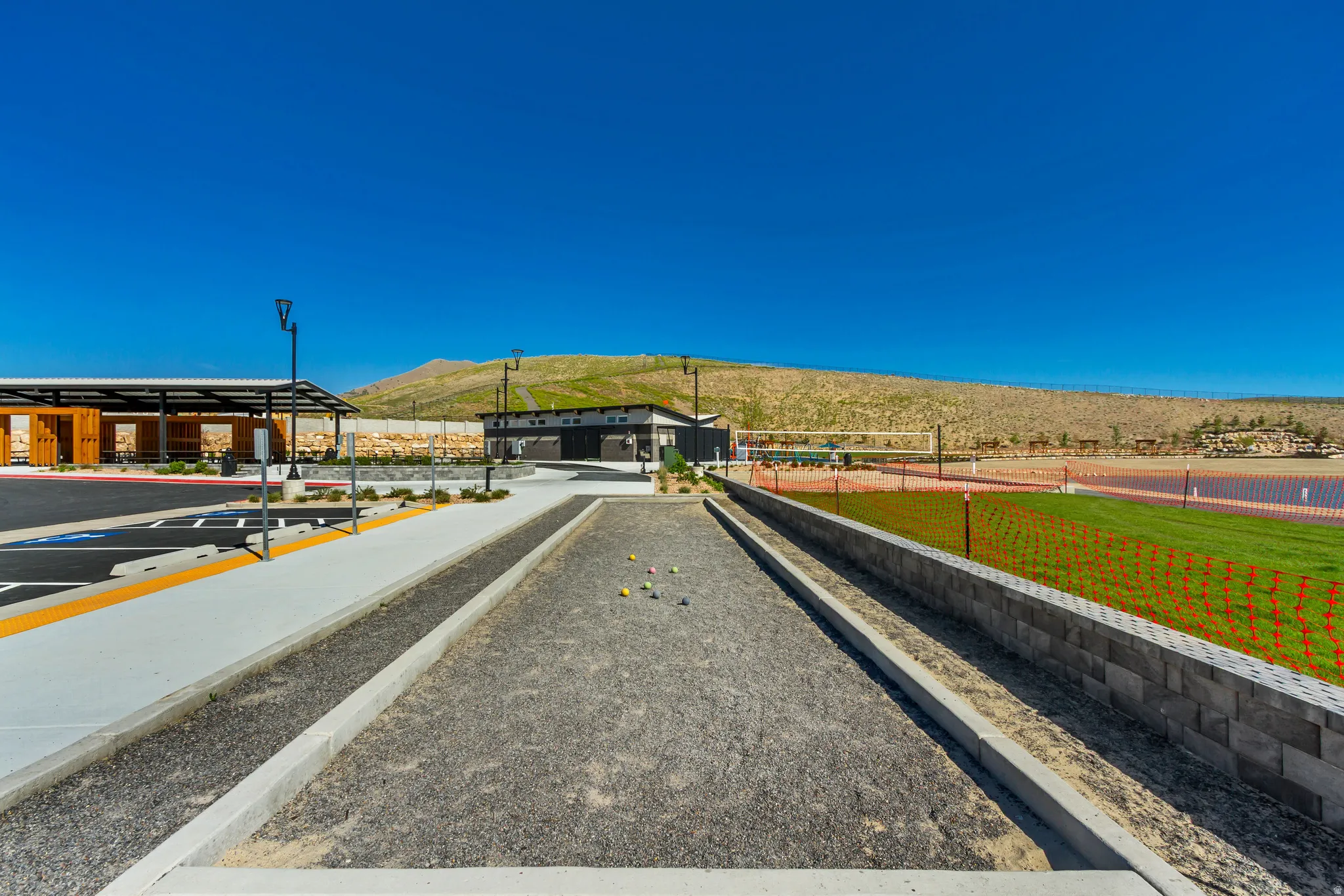 Bocce ball court featuring gravel surface, concrete borders, and adjacent block retaining wall