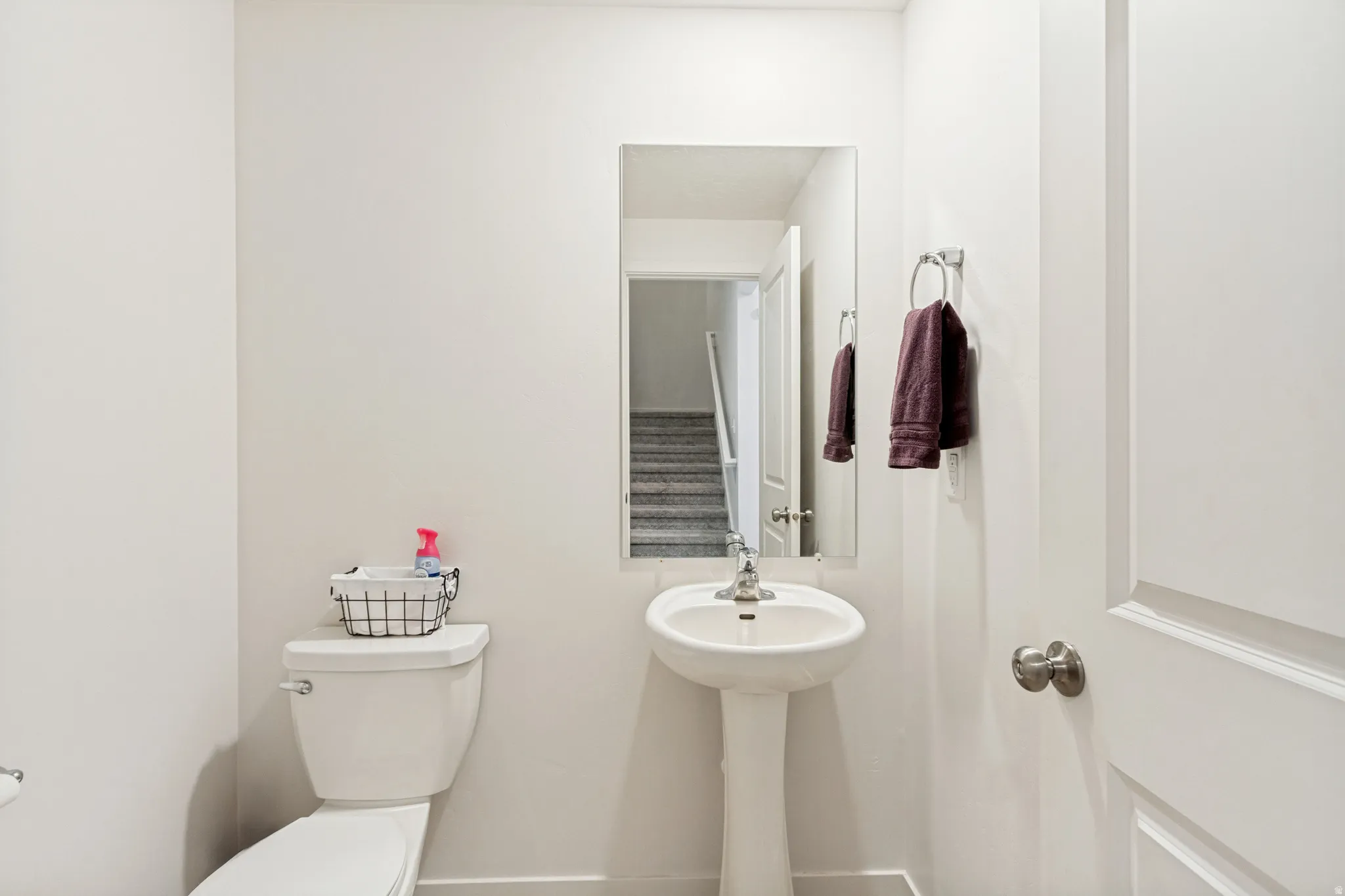 White pedestal sink with a single-handle faucet, rectangular mirror, and a towel ring