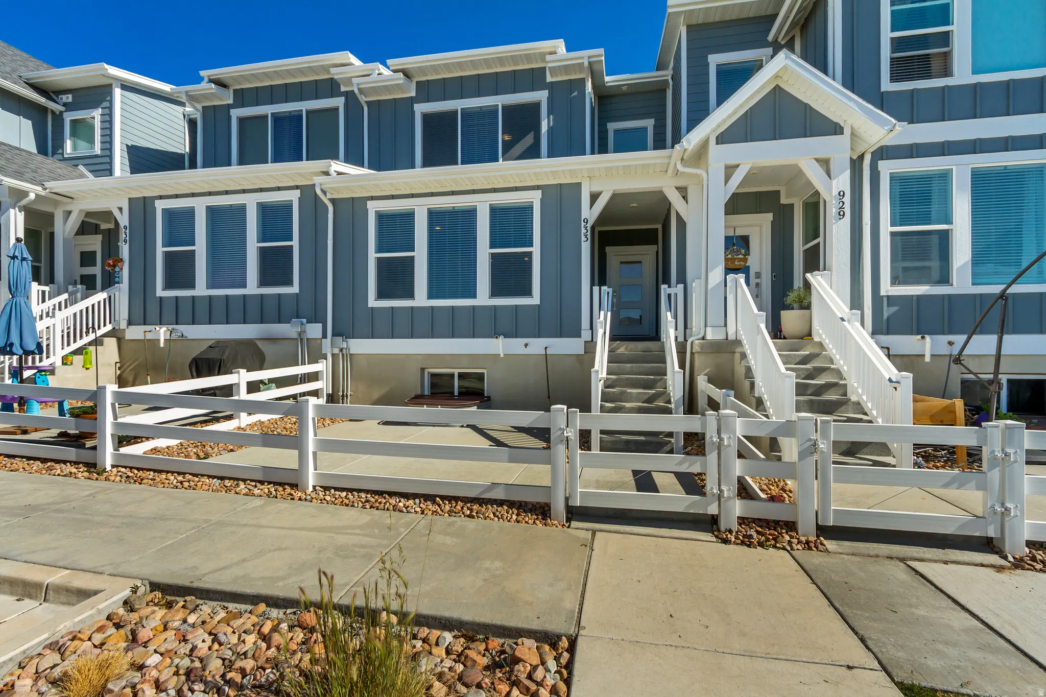 Modern townhome exterior featuring gray vertical siding, white trim, and multiple large windows