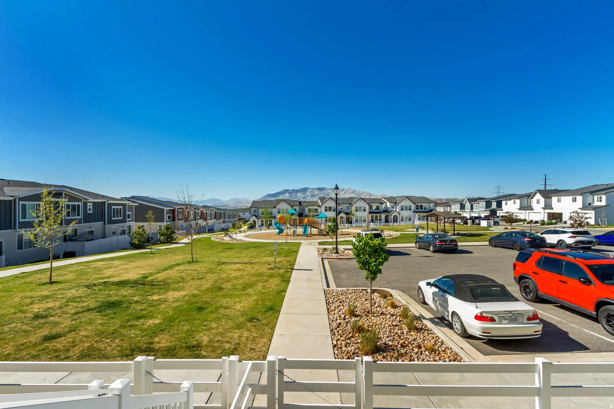 Expansive green space featuring a playground, paved walking paths, and mature landscaping