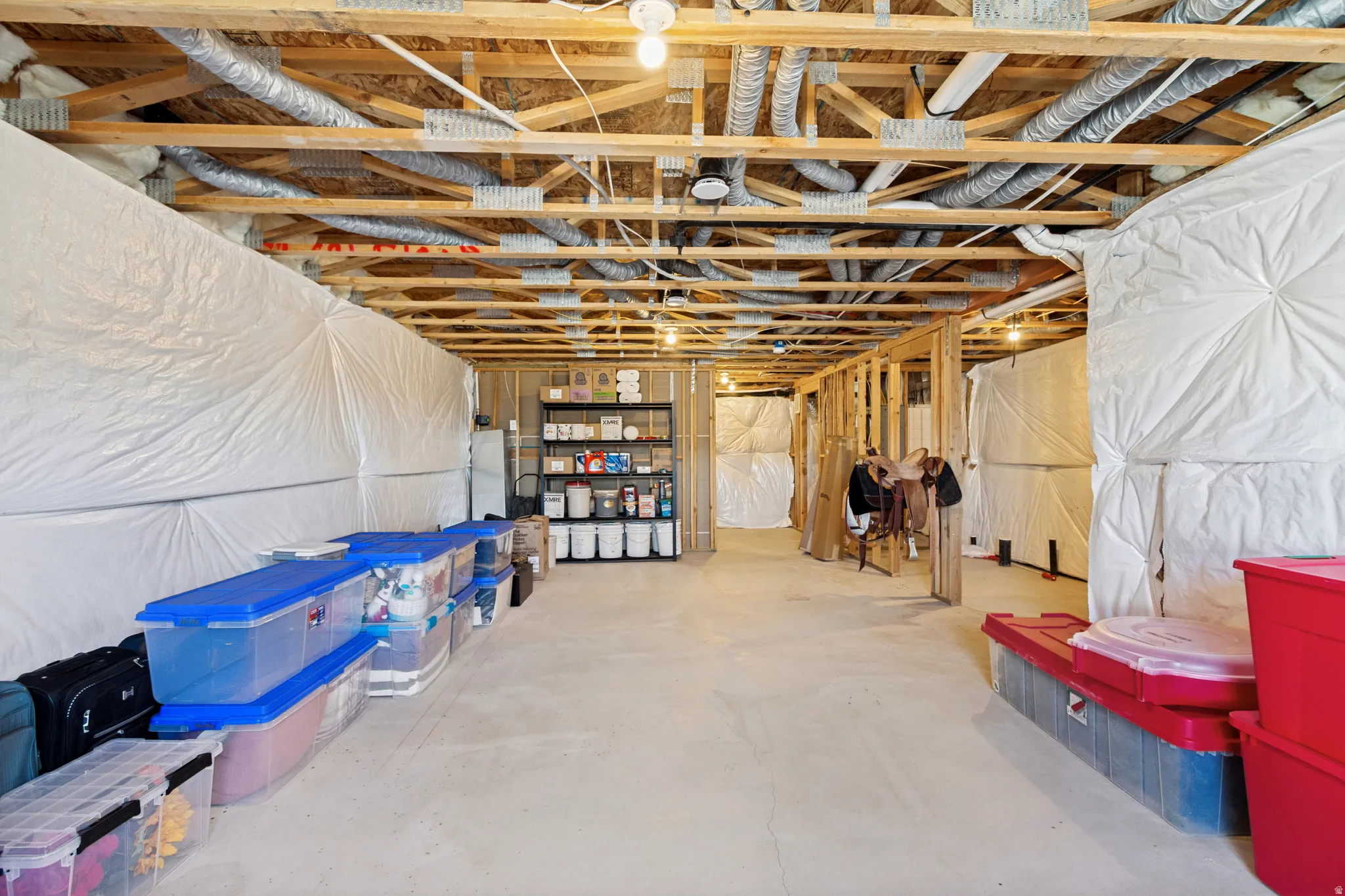 Unfinished basement offering substantial storage space, exposed wooden ceiling joists, and concrete flooring