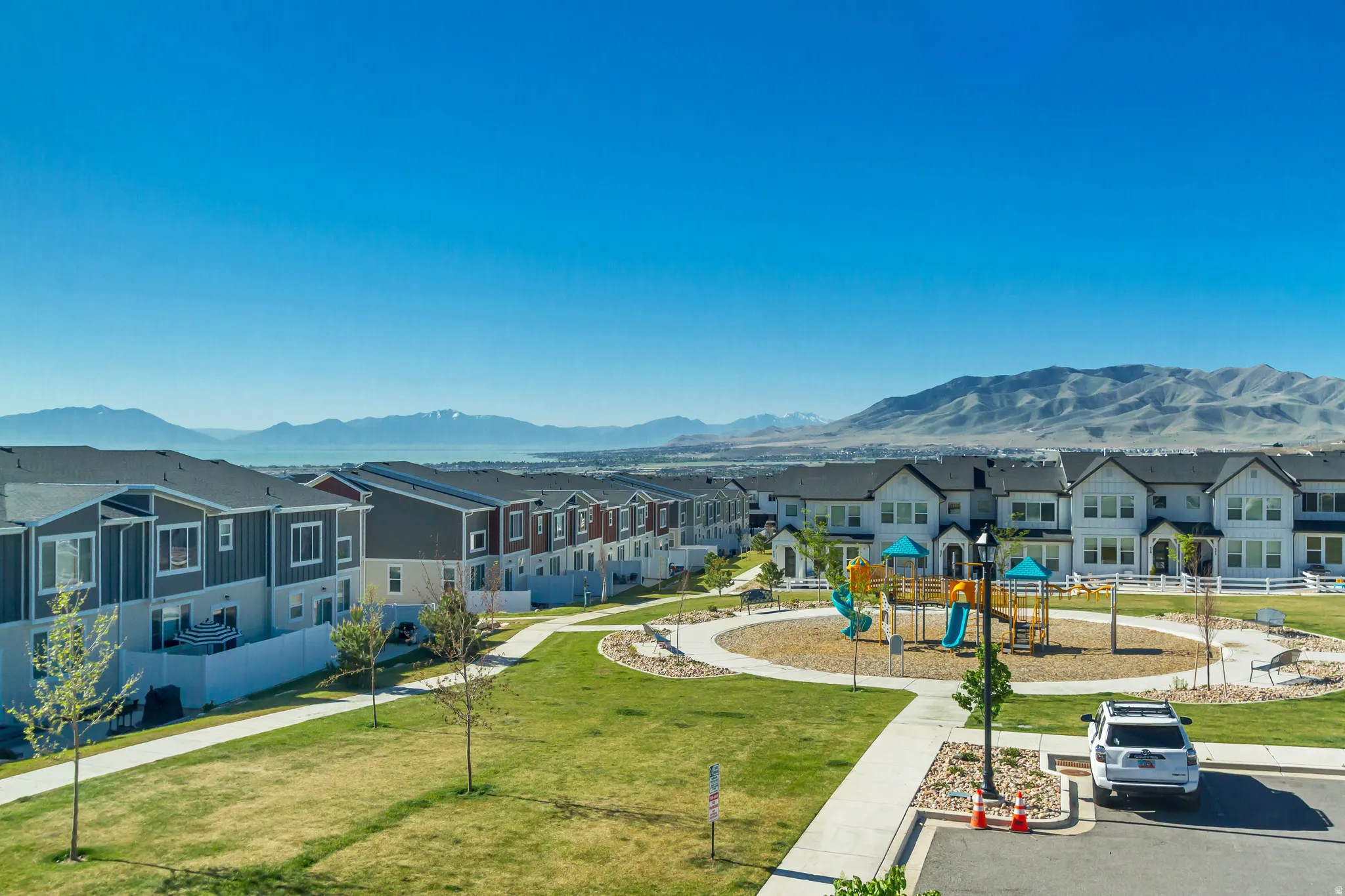 Expansive green spaces featuring a circular playground area with slides, swings, and climbing structures