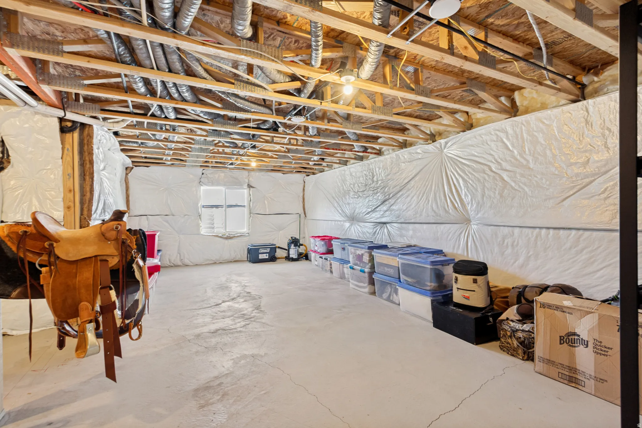 Unfinished basement offering exposed ceiling joists, concrete flooring, and insulated walls with a small, visible window