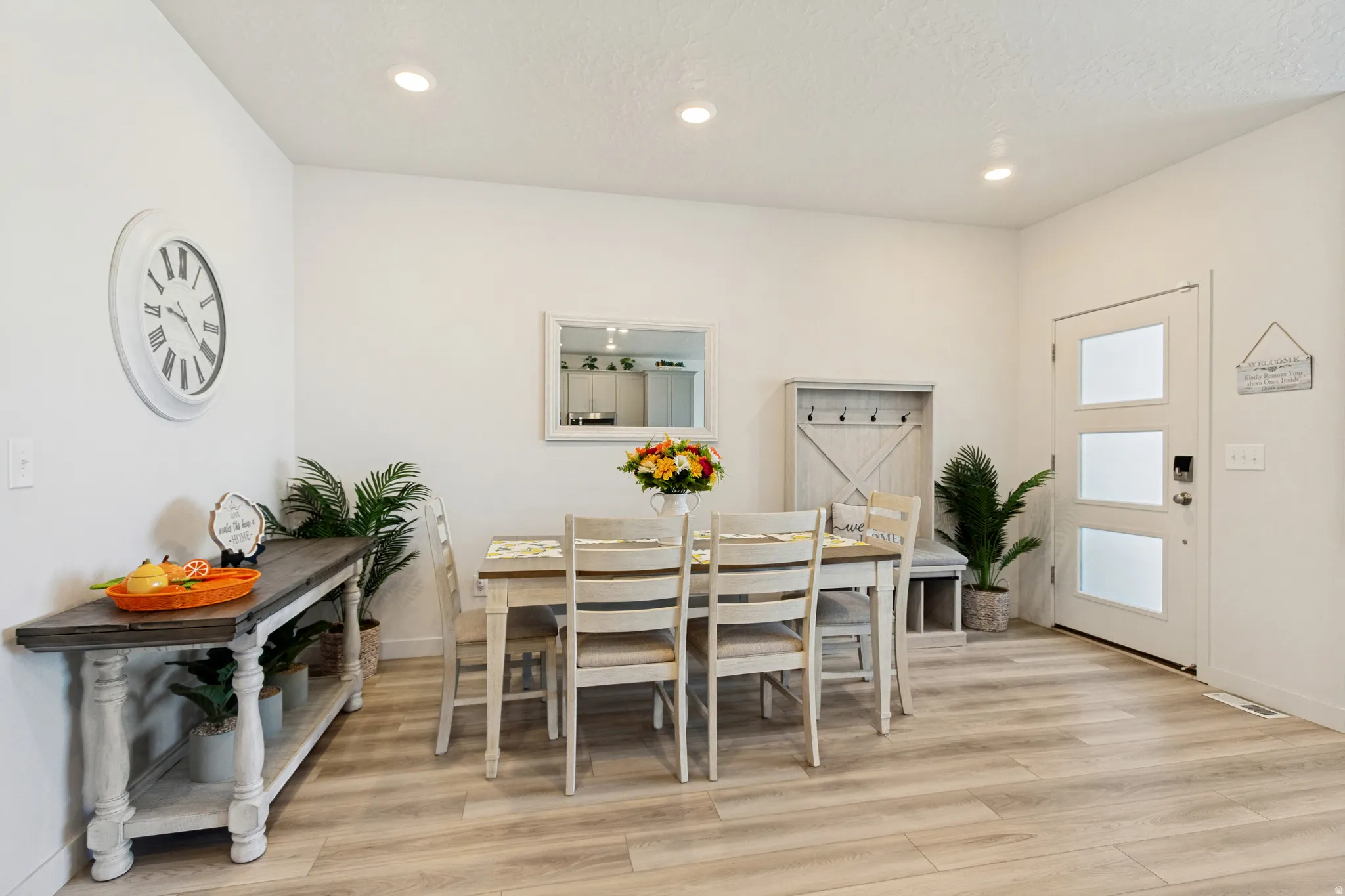 Dining area featuring wood-finish flooring, recessed lighting, and a modern entry door with frosted panels