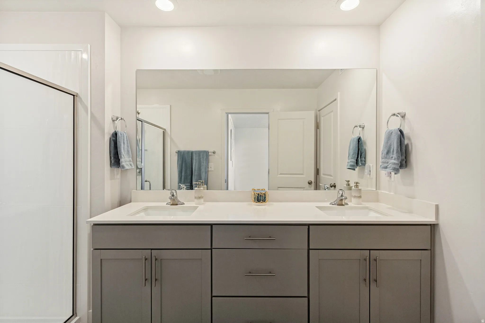 Bathroom featuring a dual vanity with gray cabinetry, a light-colored countertop, and two undermount sinks