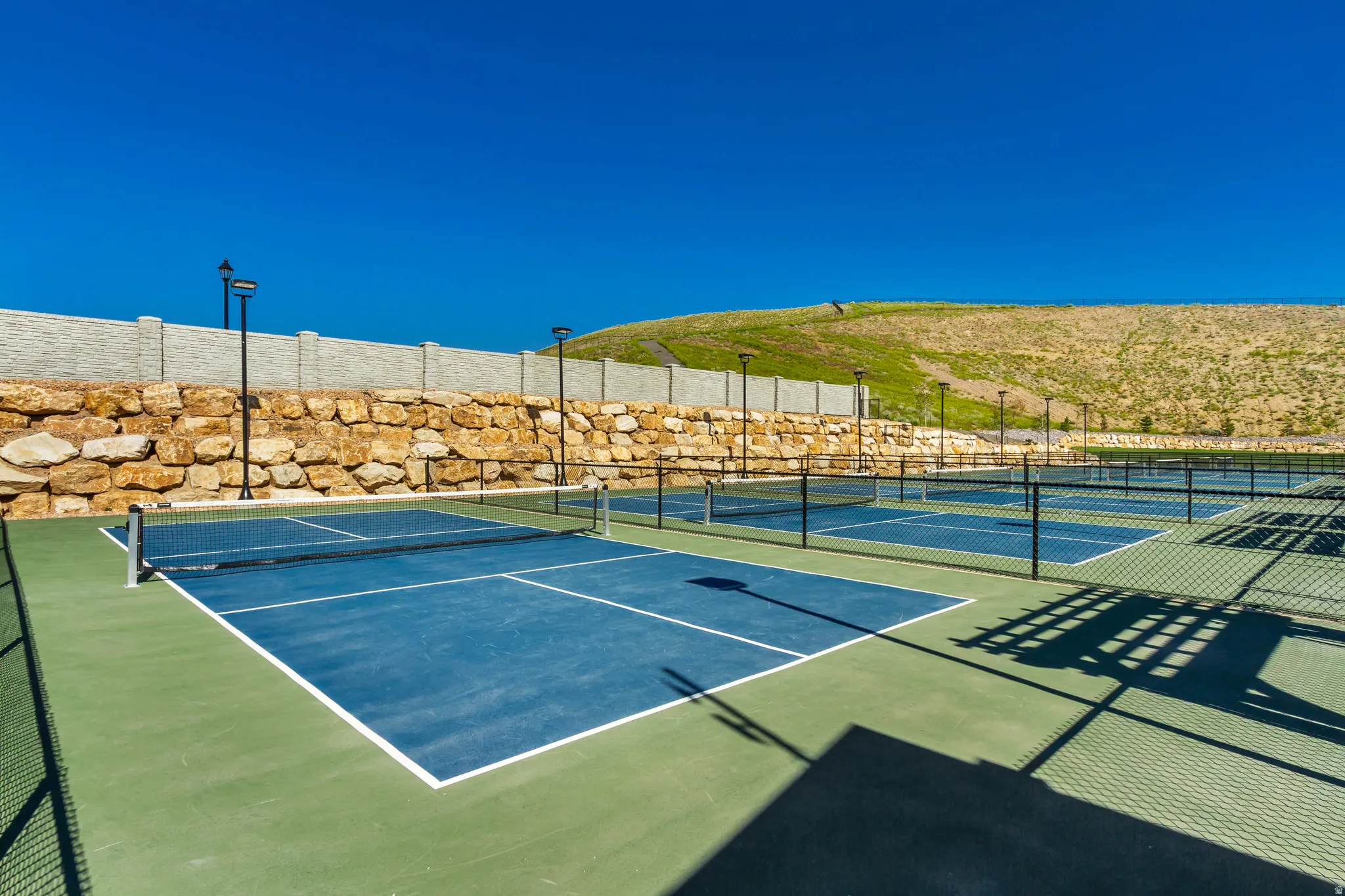 Multiple hard-surface courts with dark blue playing areas and light green surrounds
